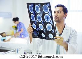Doctor reviewing MRI scans in hospital room Doctor reviewing MRI scans in hospital room