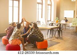 Casual business people joining hands in meeting in office