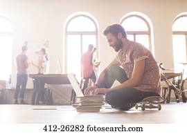 Casual businessman working at laptop from skateboard