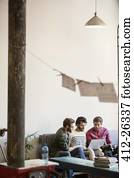 Casual businessmen working at laptop on sofa in office