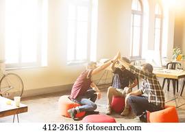 Creative business people joining hands in circle in sunny office