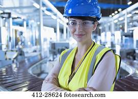 Portrait confident female worker with hard-hat and protective eyewear in factory