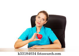 Young female doctor holding toy heart