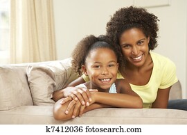 Mother And Daughter Relaxing On Sofa At Home Mother And Daughter Relaxing On Sofa At Home