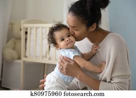 Loving biracial mom hug and kiss little baby Loving biracial mom hug and kiss little baby