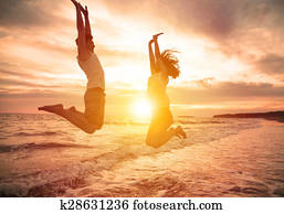 young happy couple jumping on beach 