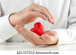 Caring man cupping a red heart in his hands