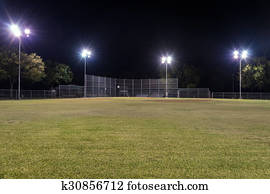 Empty baseball field at night with the lights on