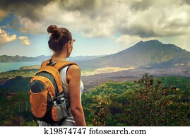 Lady tourist with a backpack standing on top of the mountain and Lady tourist with a backpack standing on top of the mountain and