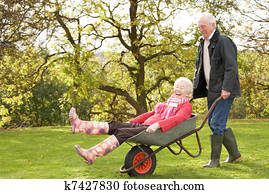 Senior Couple Man Giving Woman Ride In Wheelbarrow Senior Couple Man Giving Woman Ride In Wheelbarrow