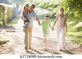 Family walking outdoors holding hands and smiling Family walking outdoors holding hands and smiling