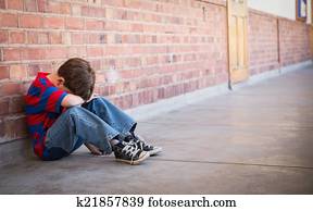 Sad pupil sitting alone in corridor