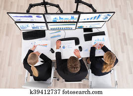 Young Businesspeople Working With Graphs On Multiple Computers