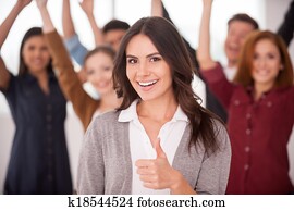 vi, ar, framgångsrik, team!, vacker, ung kvinna, visande, henne, tumme uppe, och, le, medan, grupp, av, glad, ungdomar, stående, fond, och, hålla, vapen