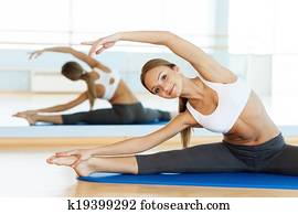 Woman stretching. Cheerful young woman warming up before training