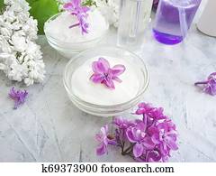 cream cosmetic flower lilac on a gray concrete background cream cosmetic flower lilac on a gray concrete background