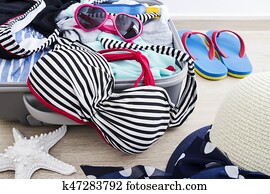 Bikini and clothes in luggage on the laminate floor Bikini and clothes in luggage on the laminate floor