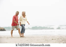 Senior Couple On Holiday Running Along Winter Beach