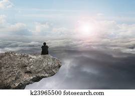 businessman sitting on cliff with natural sky daylight cloudscap
