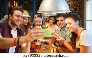 happy friends with smartphone taking selfie at bar happy friends with smartphone taking selfie at bar