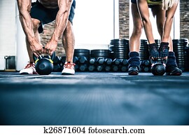 Muscular man and fit woman workout with kettle ball Muscular man and fit woman workout with kettle ball