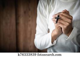 woman holding a cross in her hands and praying. Pray for blessings from God. Concept of religion faith