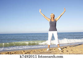 Senior Woman In Fitness Clothing Stretching On Beach