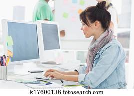 Artist using computer with colleagues behind at office Artist using computer with colleagues behind at office