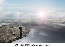 businessman hand hanging on cliff with natural sky daylight clou