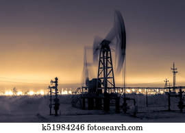 Pump jack and refinery at night. Pump jack and refinery at night.