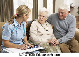 Senior Couple In Discussion With Health Visitor At Home