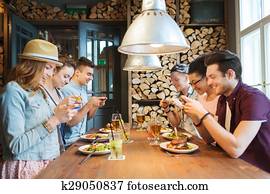happy friends with smartphones picturing food happy friends with smartphones picturing food