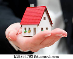 A real estate agent holding a small new house in her hands