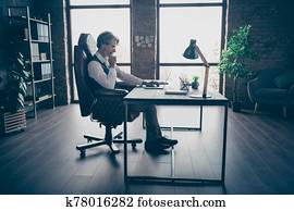 Profile side view of his he nice attractive classy chic focused skilled experienced gray-haired man economist sitting in chair working at modern loft brick industrial style interior workplace station