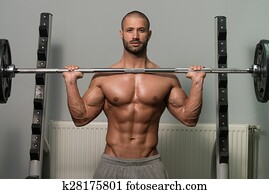 Bodybuilder Exercising Shoulders With Barbell