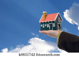 House in woman hand and sky