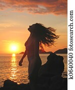 A woman in profile moving her head on her long hair at the sunset, Labuan Bajo, Pede Beach, Flores island, Indonesia A woman in profile moving her head on her long hair at the sunset, Labuan Bajo, Pede Beach, Flores island, Indonesia