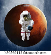 Astronaut, holding a planet Earth in hand on against of Mars