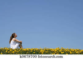Girl sitting in dandelion field