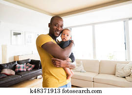 Young afro-american father holding his baby son in the arms