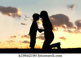 Mother Lovingly Kissing Little Child at Sunset Mother Lovingly Kissing Little Child at Sunset