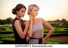 Two well-dressed woman in a beautiful park.