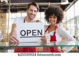 Smiling team posing with open sign Smiling team posing with open sign