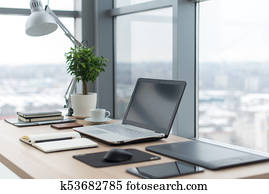 Workplace with notebook laptop Comfortable work table in office windows and city view.