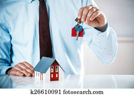 Agent Holding Key with Miniature Home on the Table