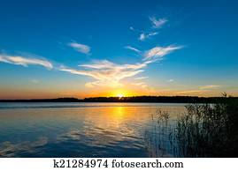 tranquil lake and the setting sun over the horizon