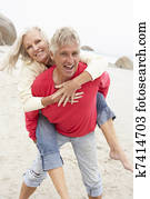 Senior Man Giving Woman Piggyback On Winter Beach