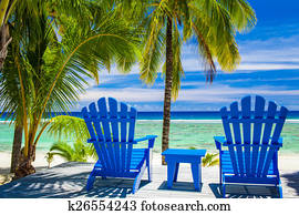 Blue chairs on a beach front on amazing beach