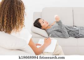 Therapist writing notes on her upset patient on the couch