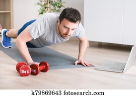Man doing exercise while watching tutorial on laptop at home Man doing exercise while watching tutorial on laptop at home